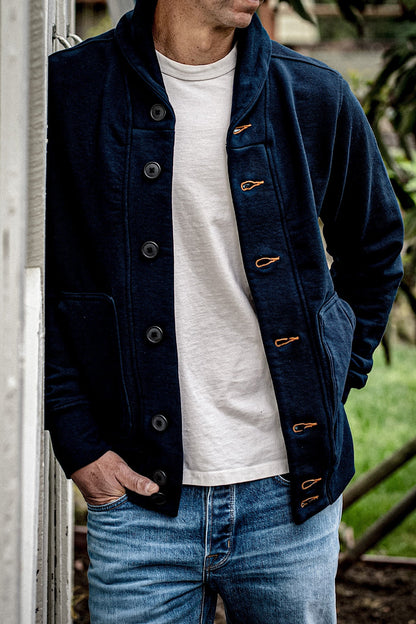 Navy French terry shawl cardigan with tobacco contrast keyholes, worn open over a cream tee and faded jeans.