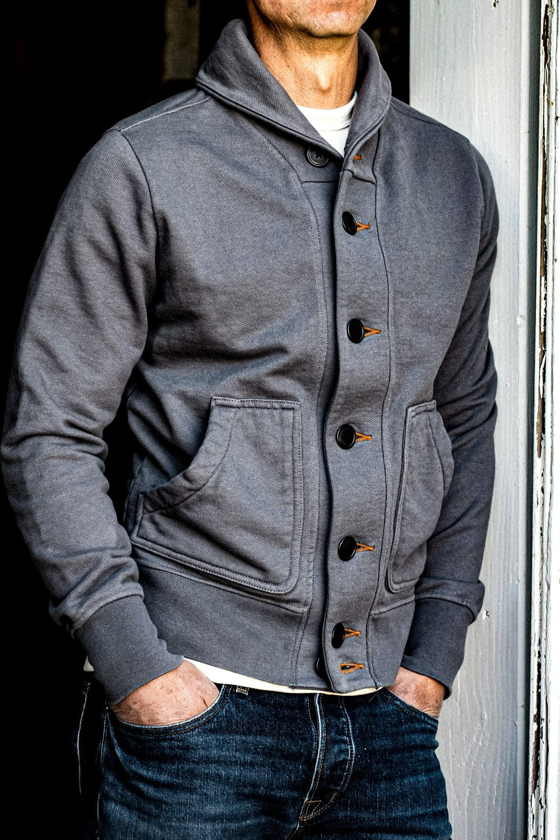 Pebble grey French terry shawl collar cardigan worn with raw denim jeans, buttoned with tobacco keyholes.