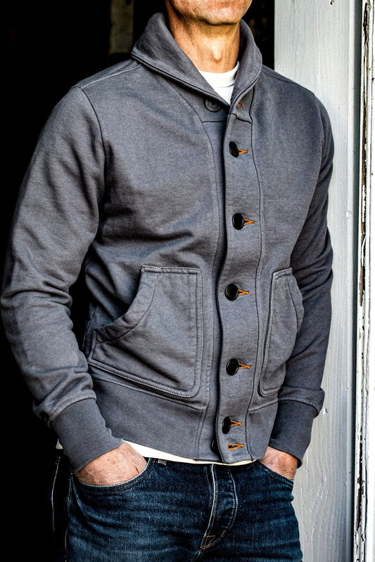 Pebble grey French terry shawl collar cardigan worn with raw denim jeans, buttoned with tobacco keyholes.