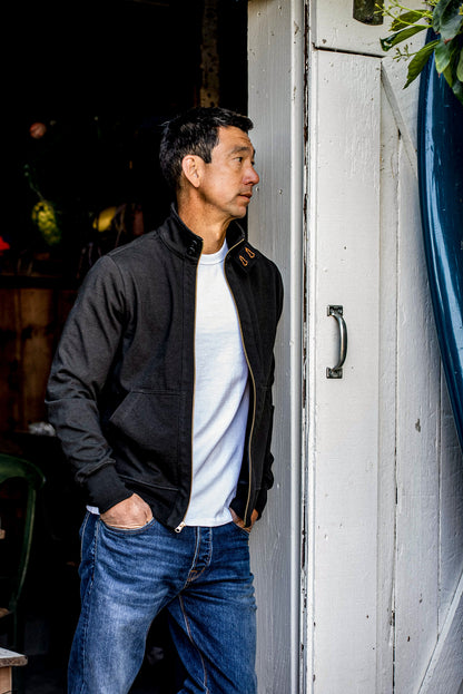 Man in charcoal Stinson cotton moto jacket, worn open over a white tee with jeans.