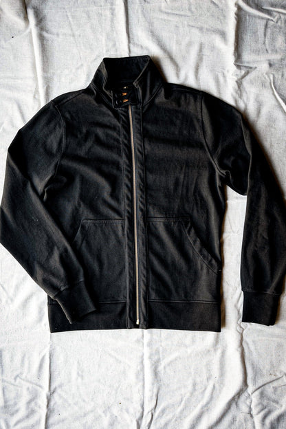 Basalt black cotton moto jacket laid flat with stand collar and brass front zipper.