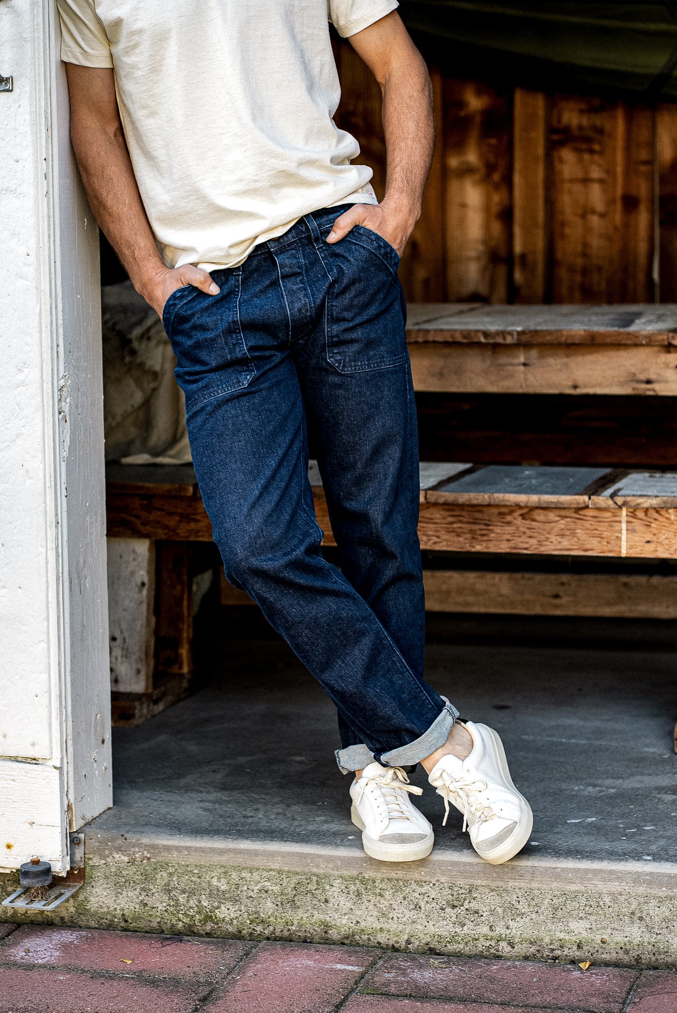 Back view of ocean wash military-style denim jeans with patch pockets and cuffed hems, worn with white sneakers.