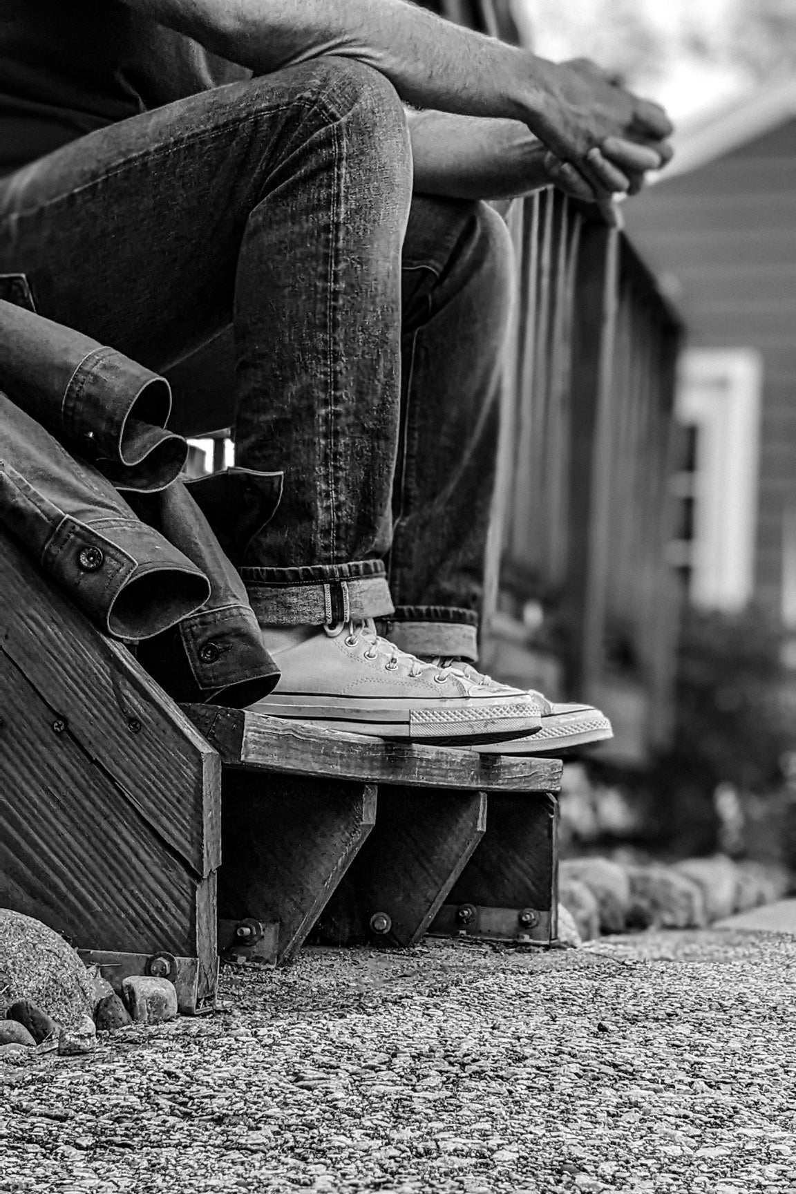 Designer jeans for men captured in black and white, featuring a slim fit with rolled cuffs and rugged texture, paired with canvas sneakers for a timeless, casual look