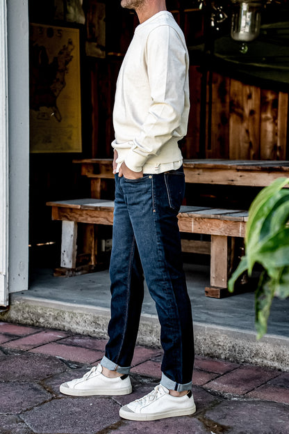 Side view of Paul ocean wash straight slim jeans with cuffed selvedge hem, worn with sneakers.