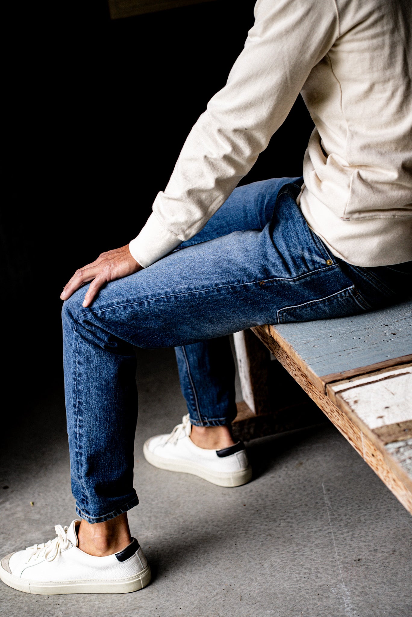 Close-up of a man sitting wearing men's premium denim jeans and white sneakers