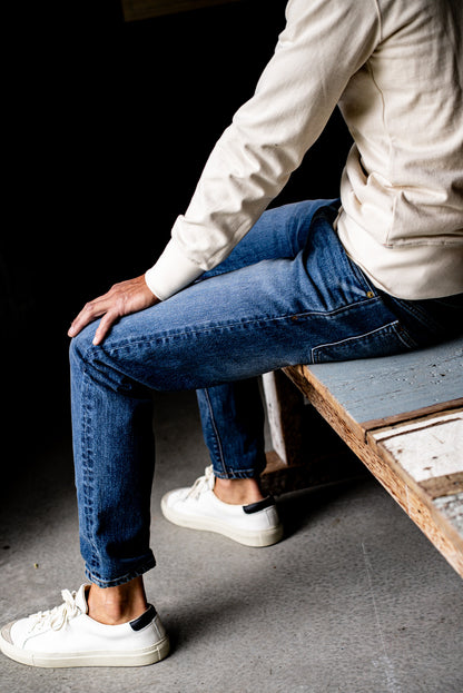 Close-up of a man sitting wearing men's premium denim jeans and white sneakers