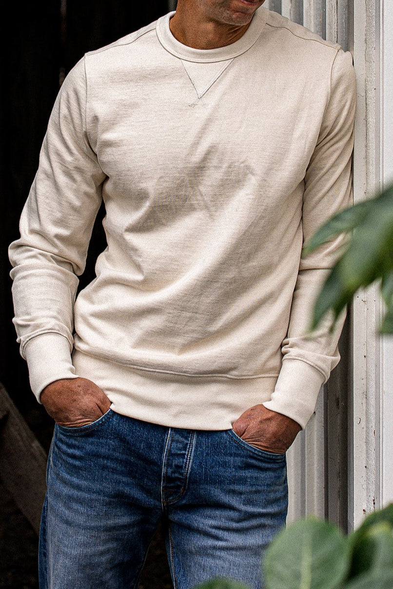 Natural cotton rugby jersey pullover worn with blue denim jeans, hands in pockets.