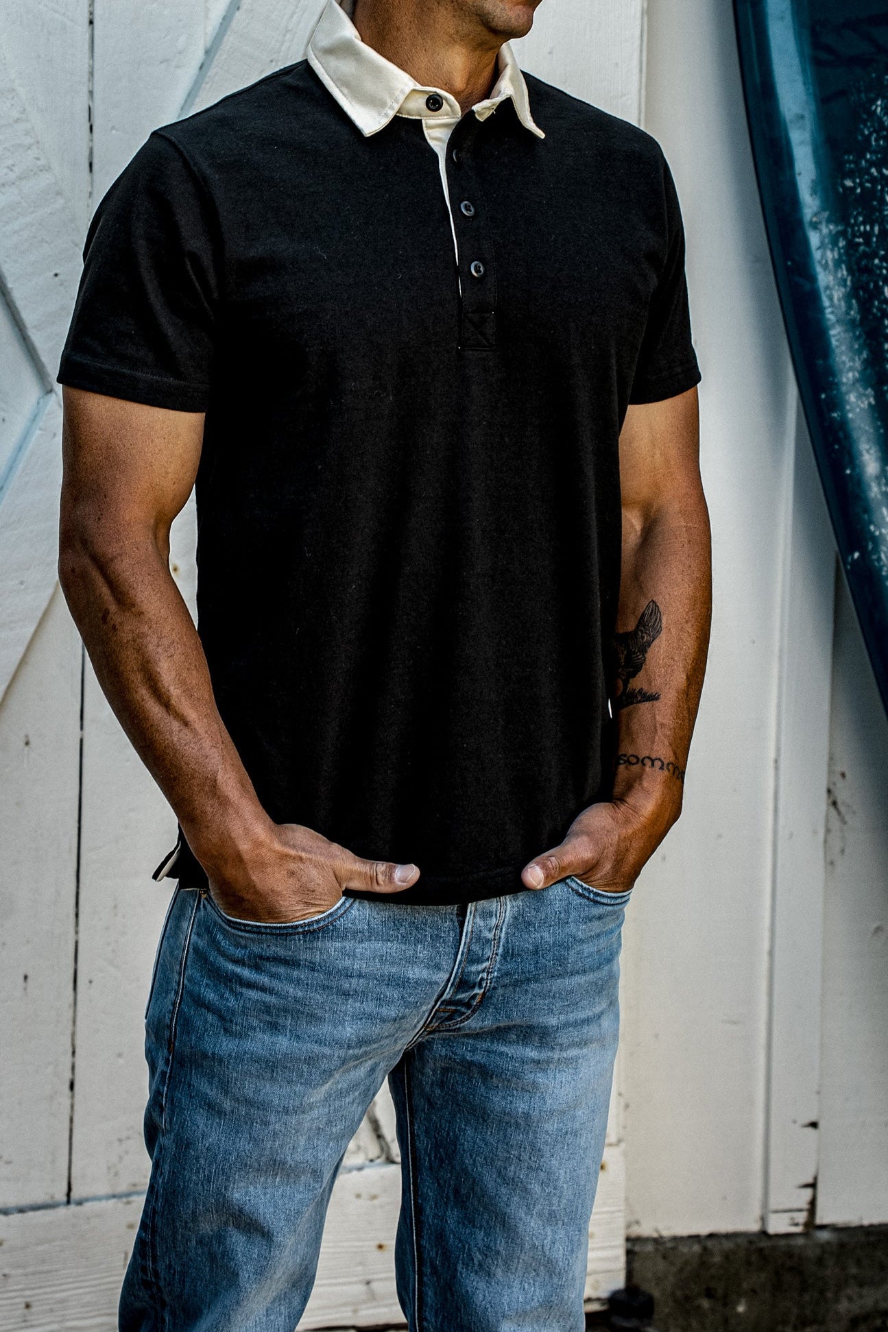Men's black rugby polo shirt with cream contrast collar, paired with jeans