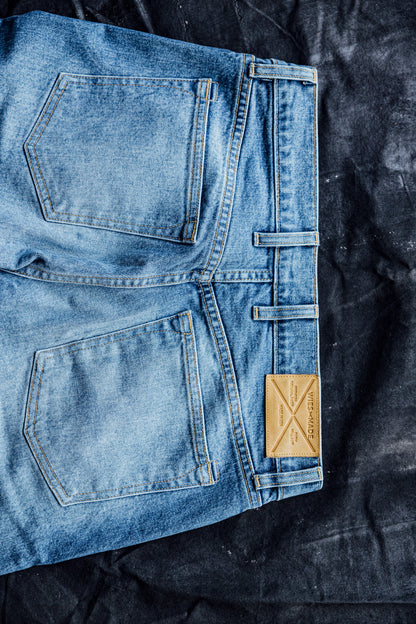 Folded salt wash American made denim jeans showing back pockets and leather WiesMade patch.