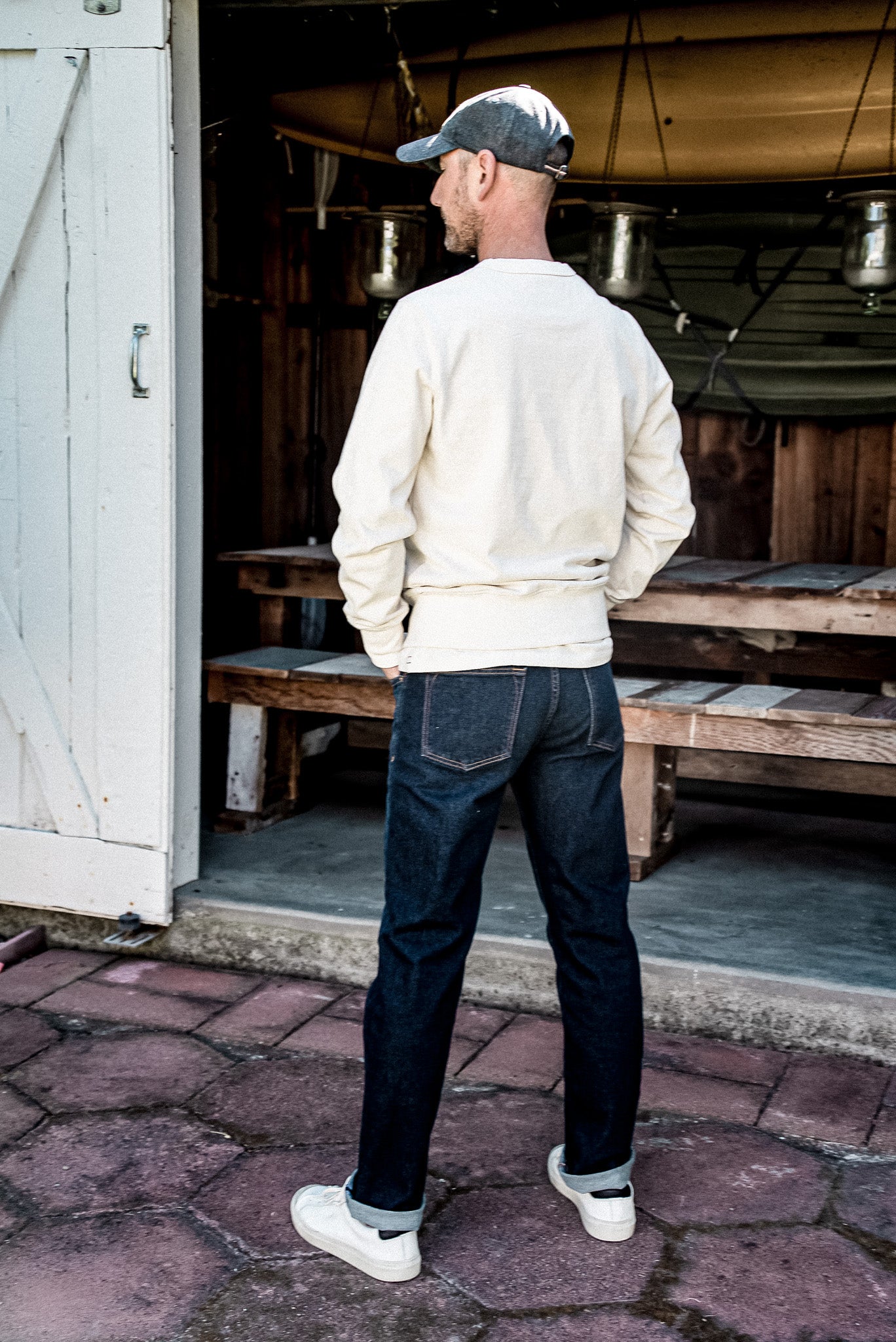 Rear view of Sam ocean wash denim jeans, cuffed hems worn with white sneakers.