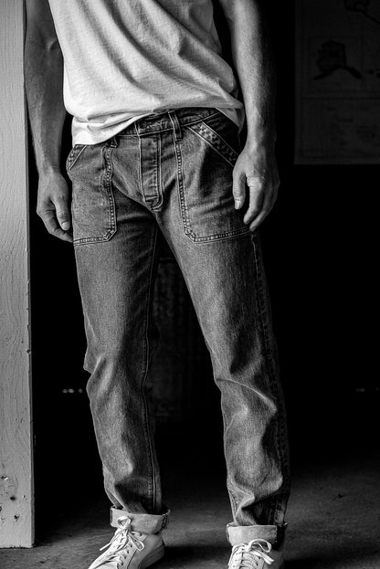Model wearing Scout military-style denim jeans with front utility pockets and cuffed hems, paired with a white tee and.