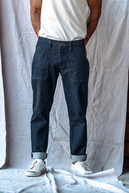 Selvedge denim jeans with a relaxed fit and cuffed hems, worn by a man paired with a white t-shirt and sneakers.