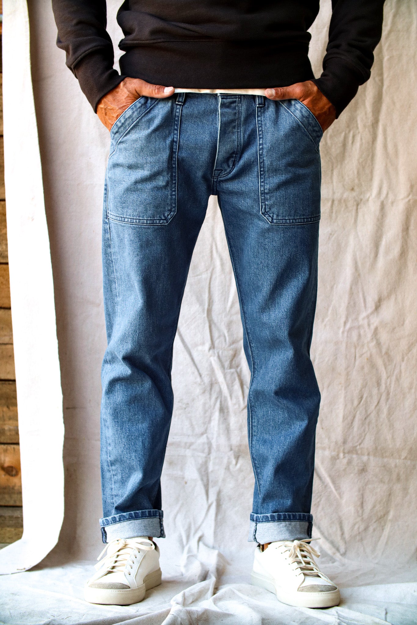 Salt-wash Scout military jeans on model with cuffed hems, patch pockets, and white sneakers.