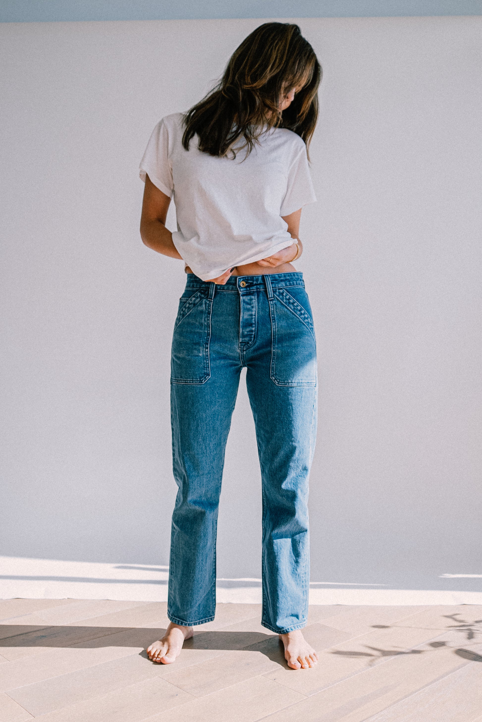 Luxury denim jeans for women styled with a white tee, featuring a high rise fit, straight leg silhouette, and front utility seams for a sophisticated, casual look