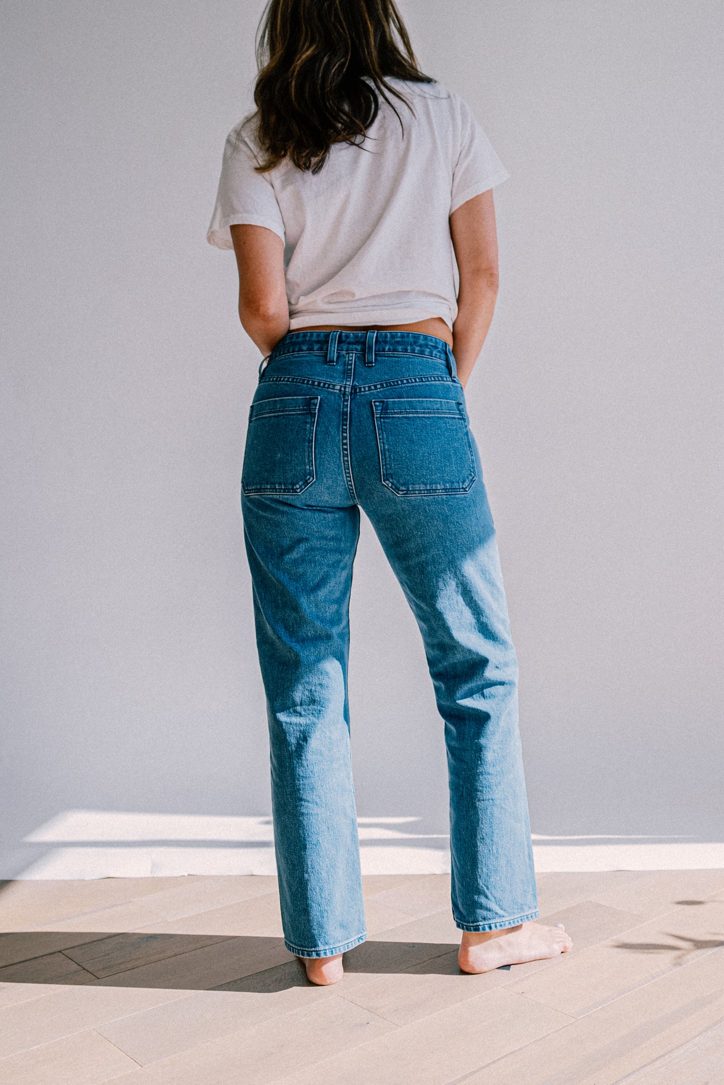 Women’s salt wash designer jeans shown from the back, featuring a high waist fit, straight leg cut, and large back pockets for a clean, modern silhouette