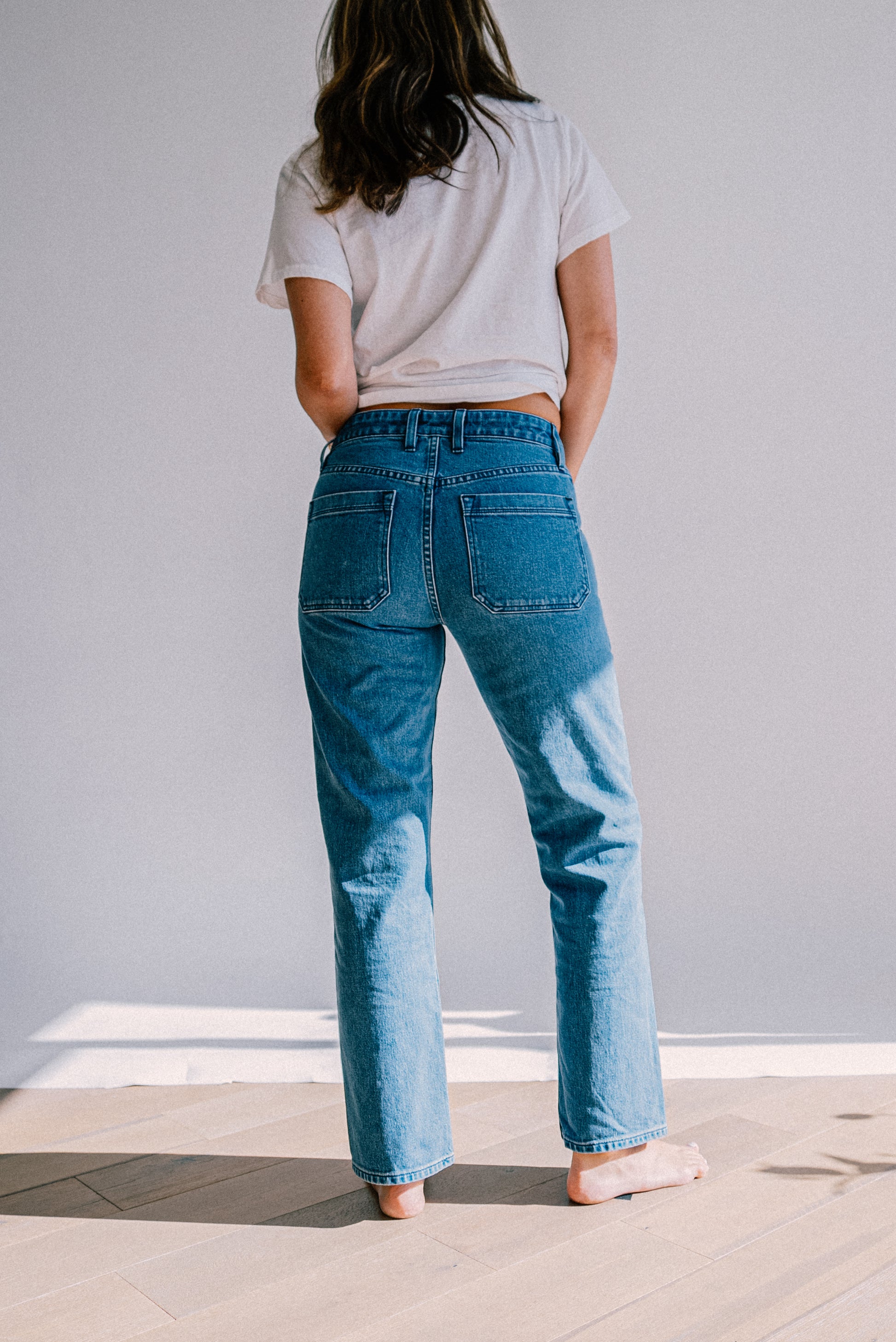 Women’s salt wash designer jeans shown from the back, featuring a high waist fit, straight leg cut, and large back pockets for a clean, modern silhouette