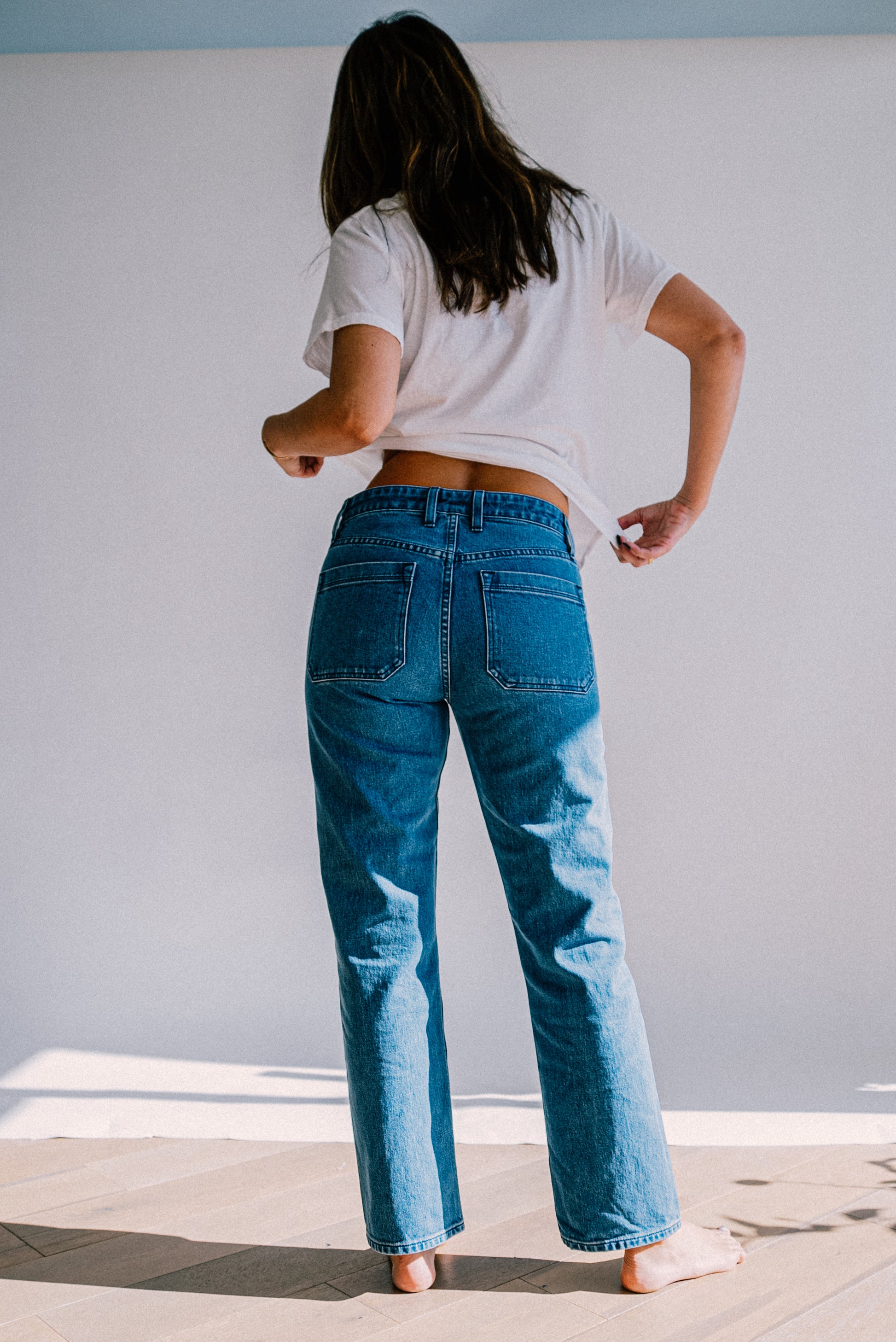 Women’s premium light blue jeans shown from the back, featuring a high rise fit, straight leg design, and structured back pockets for a clean, flattering silhouette