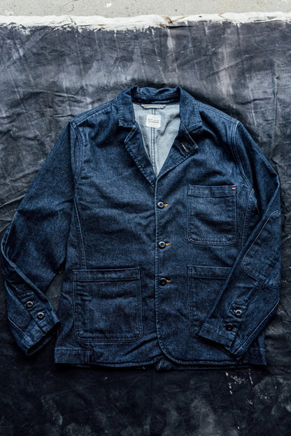 Ocean blue denim chore blazer laid flat, showing notched lapels, patch pockets, and buttoned cuffs.