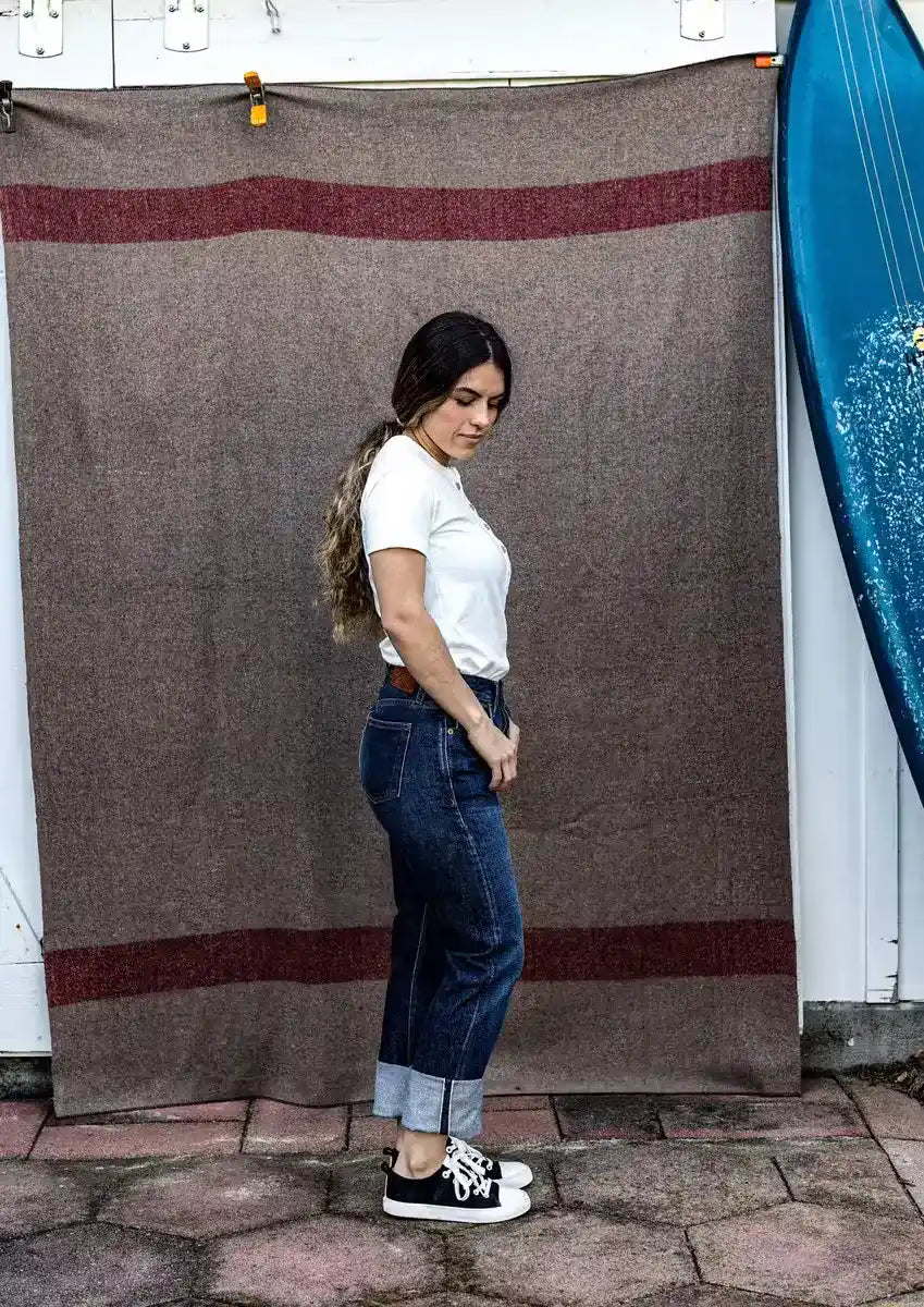 Side view of high-rise straight leg selvedge denim jeans with cuffed hem, paired with a white tee.