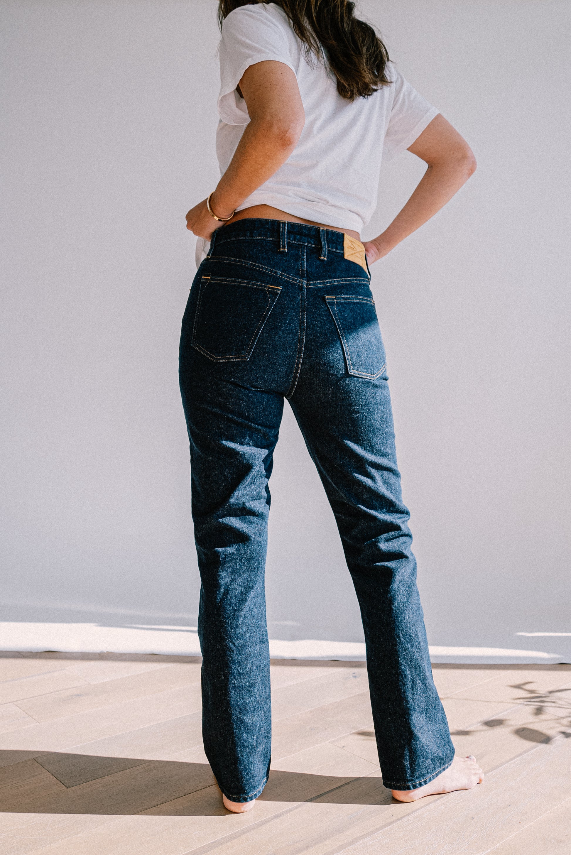 Back view of ocean wash high-rise straight-leg jeans with leather patch, paired with a white tee.