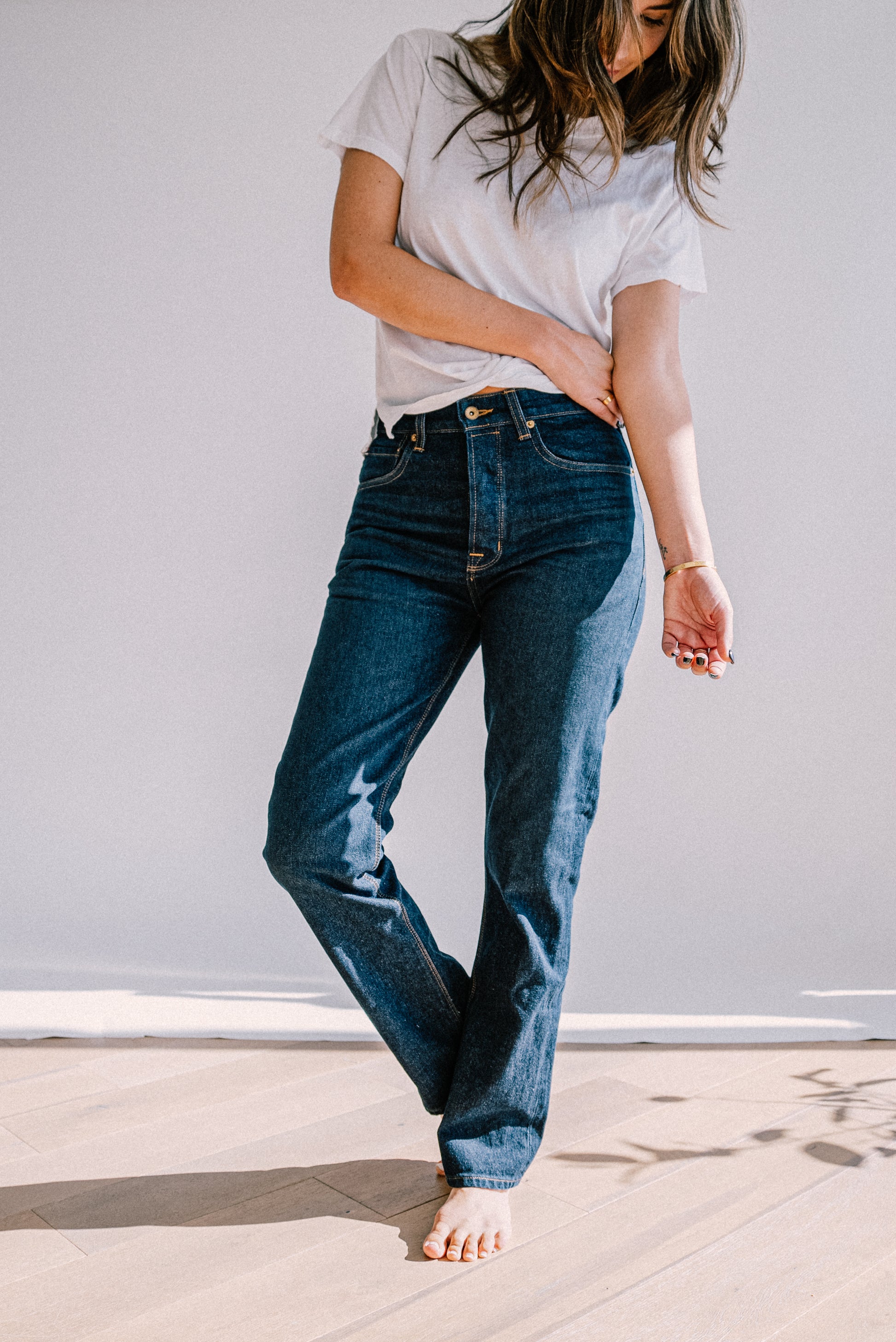 Model in high-rise straight leg American made jeans in dark ocean wash denim, styled with a white tee.