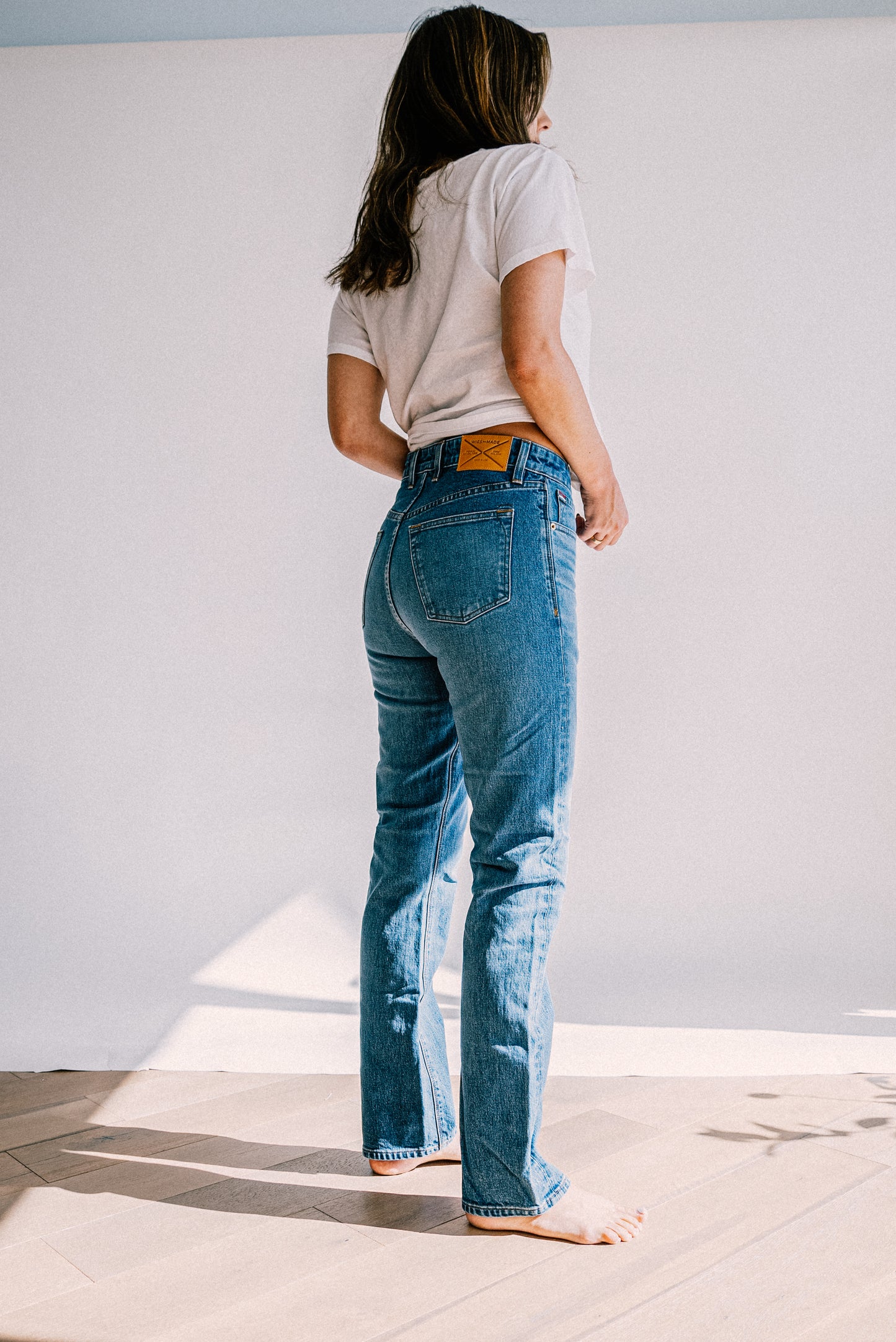 Back view of salt wash high-rise straight leg jeans with leather WiesMade patch, paired with a white tee.