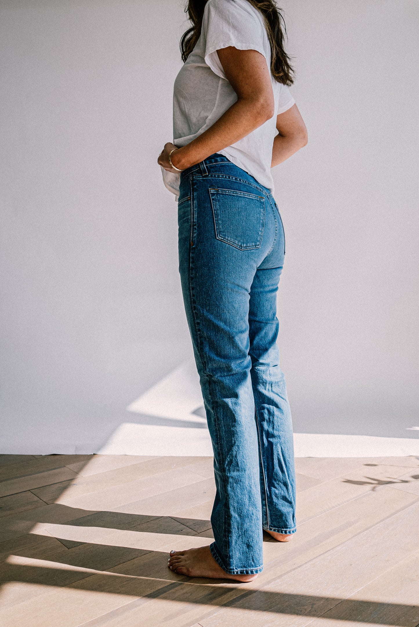 Side-back view of salt wash high-rise straight-leg American made jeans paired with a white tee.