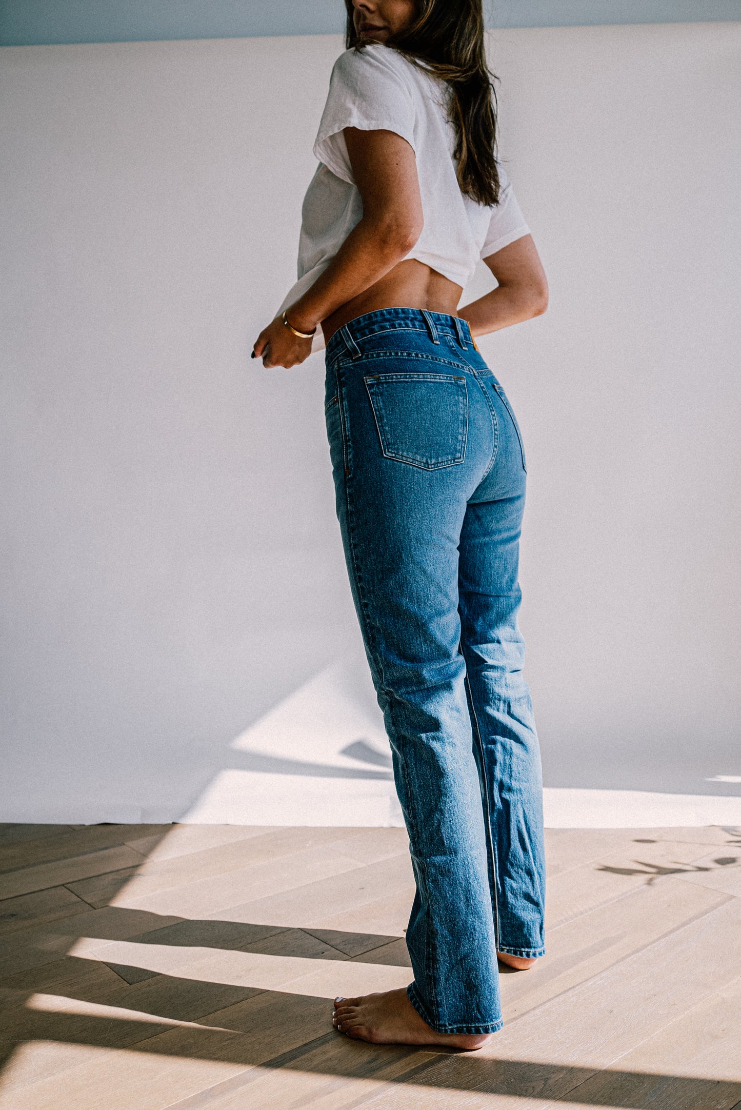 Back view of high-rise straight-leg American made denim jeans in salt wash, paired with a white tee.
