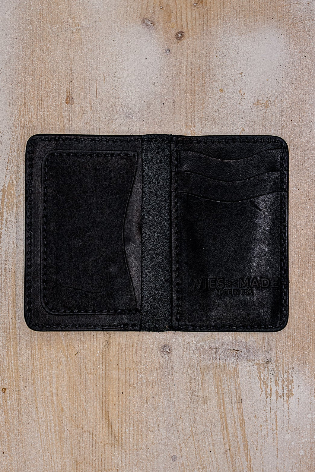 Open black Horween leather bifold wallet showing interior card slots and Made in USA stamp.