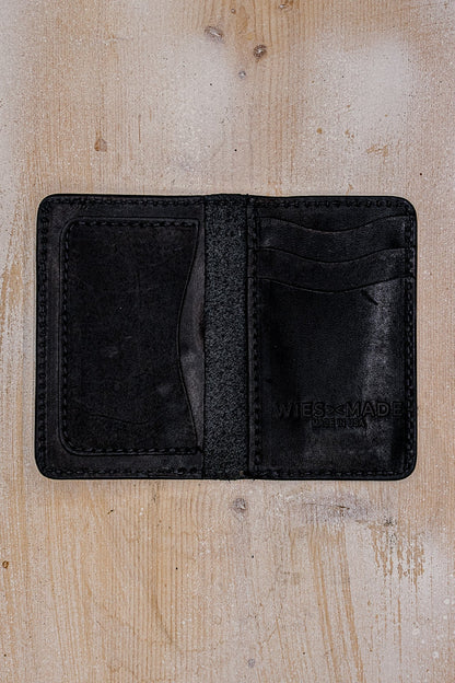 Open black Horween leather bifold wallet showing interior card slots and Made in USA stamp.