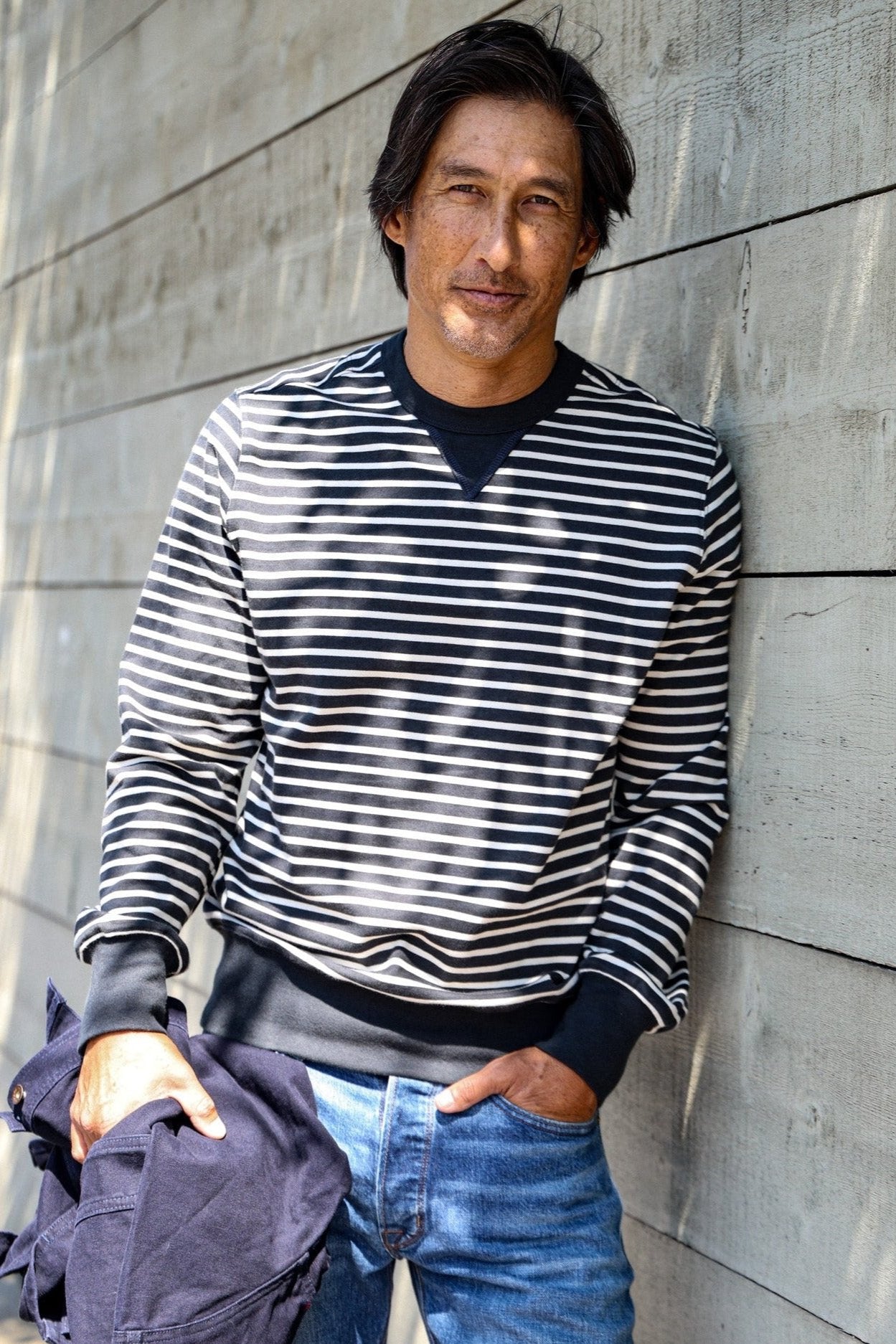 Man leaning on wood wall in navy and white striped Stinson rugby jersey pullover.