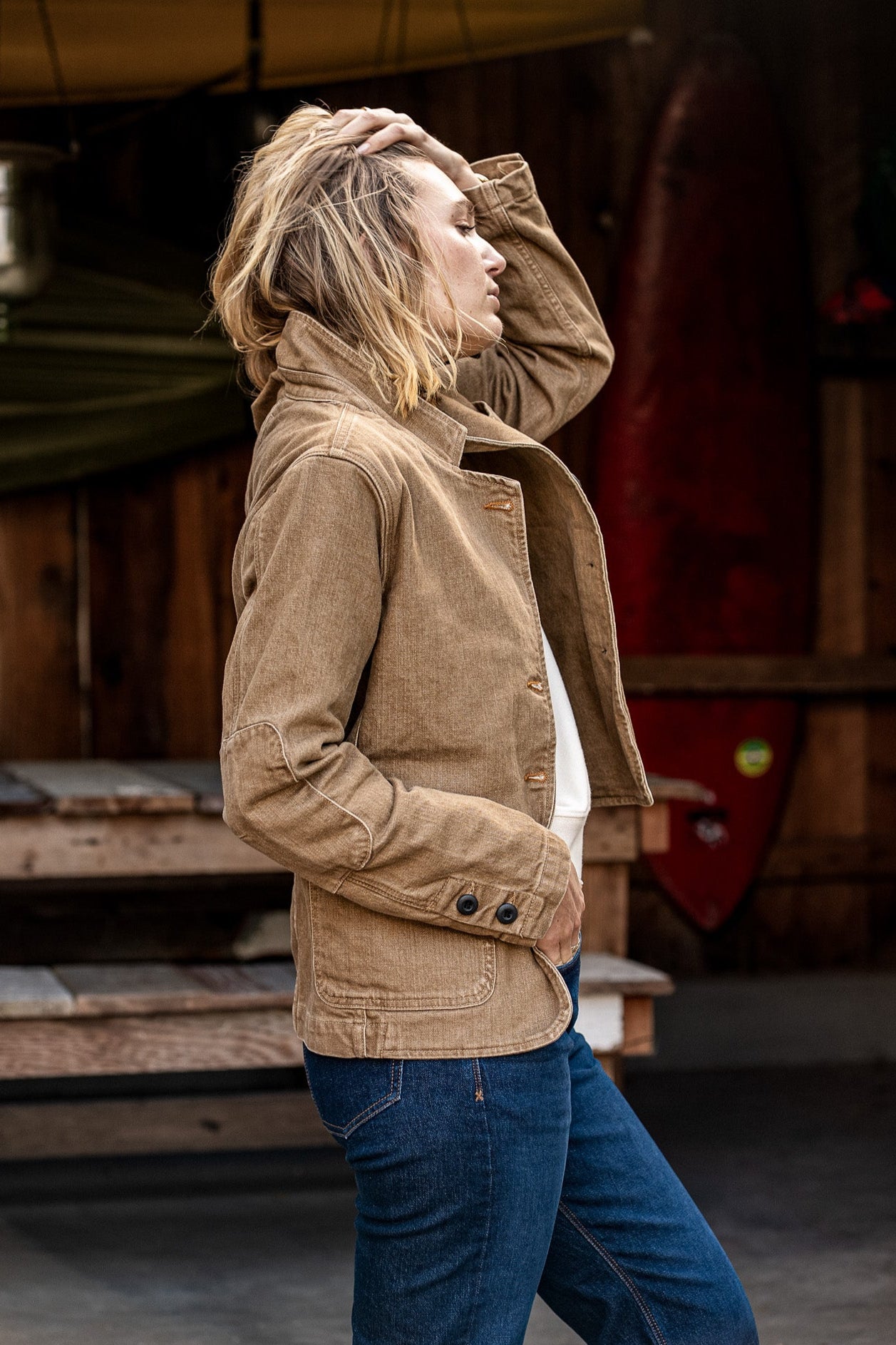 Side view of wheat denim chore blazer on a person, cuff buttons and patch pockets visible.