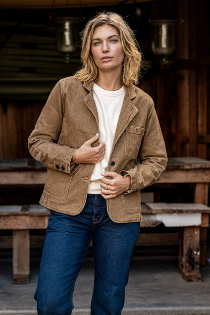 Person wearing wheat denim Scout Blazer over cream tee with blue jeans outdoors.