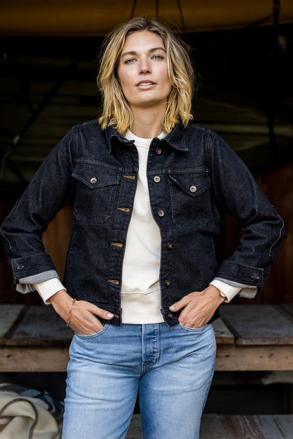 Woman wearing the black broken twill denim Artcher Jacket over a cream tee with light-wash jeans.