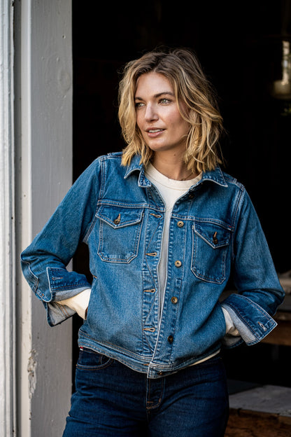 Woman wearing the Artcher broken twill denim jacket over a cream tee, standing in a doorway.