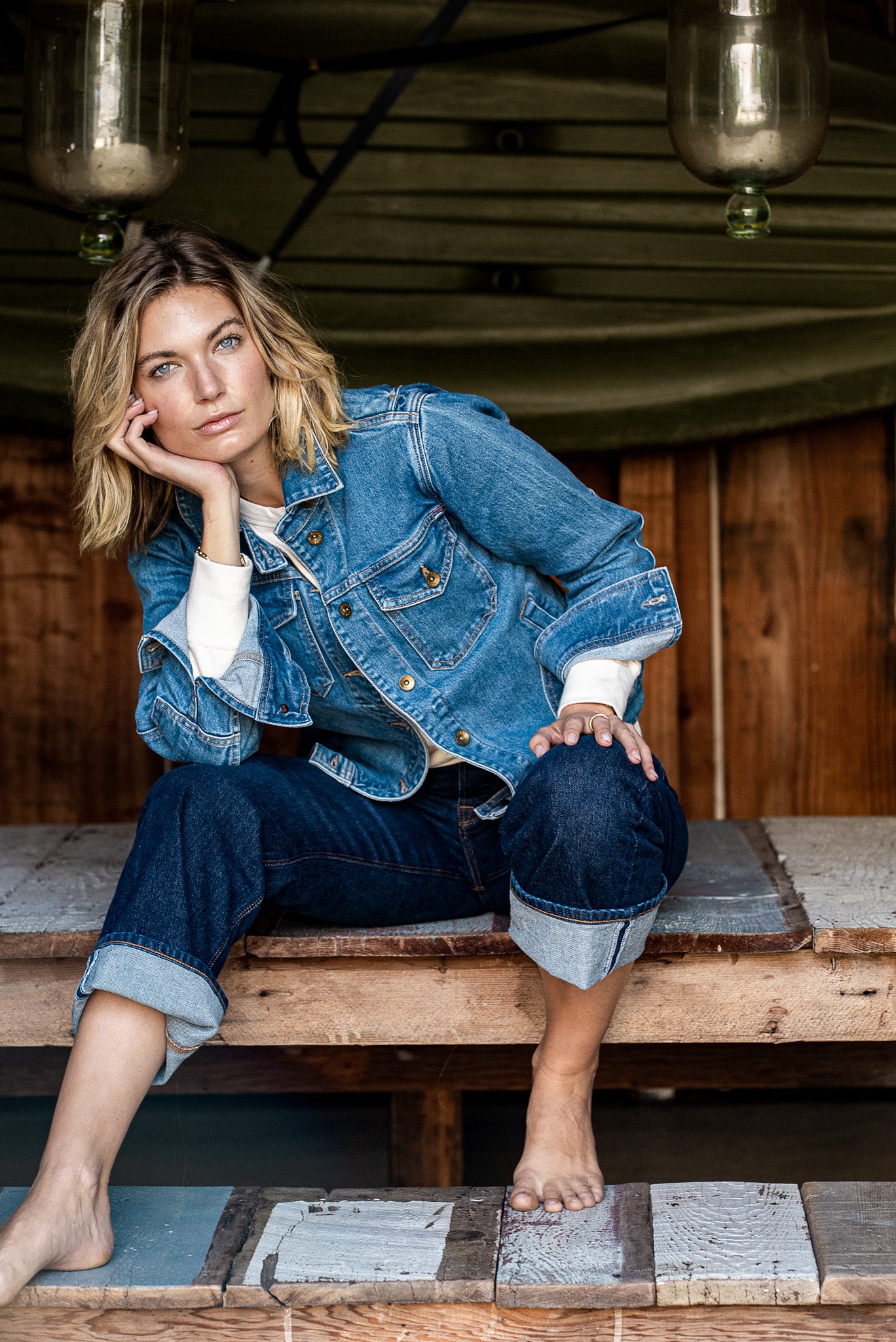 Salt-wash Artcher denim jacket worn on-model with cuffed jeans on a rustic wooden porch.