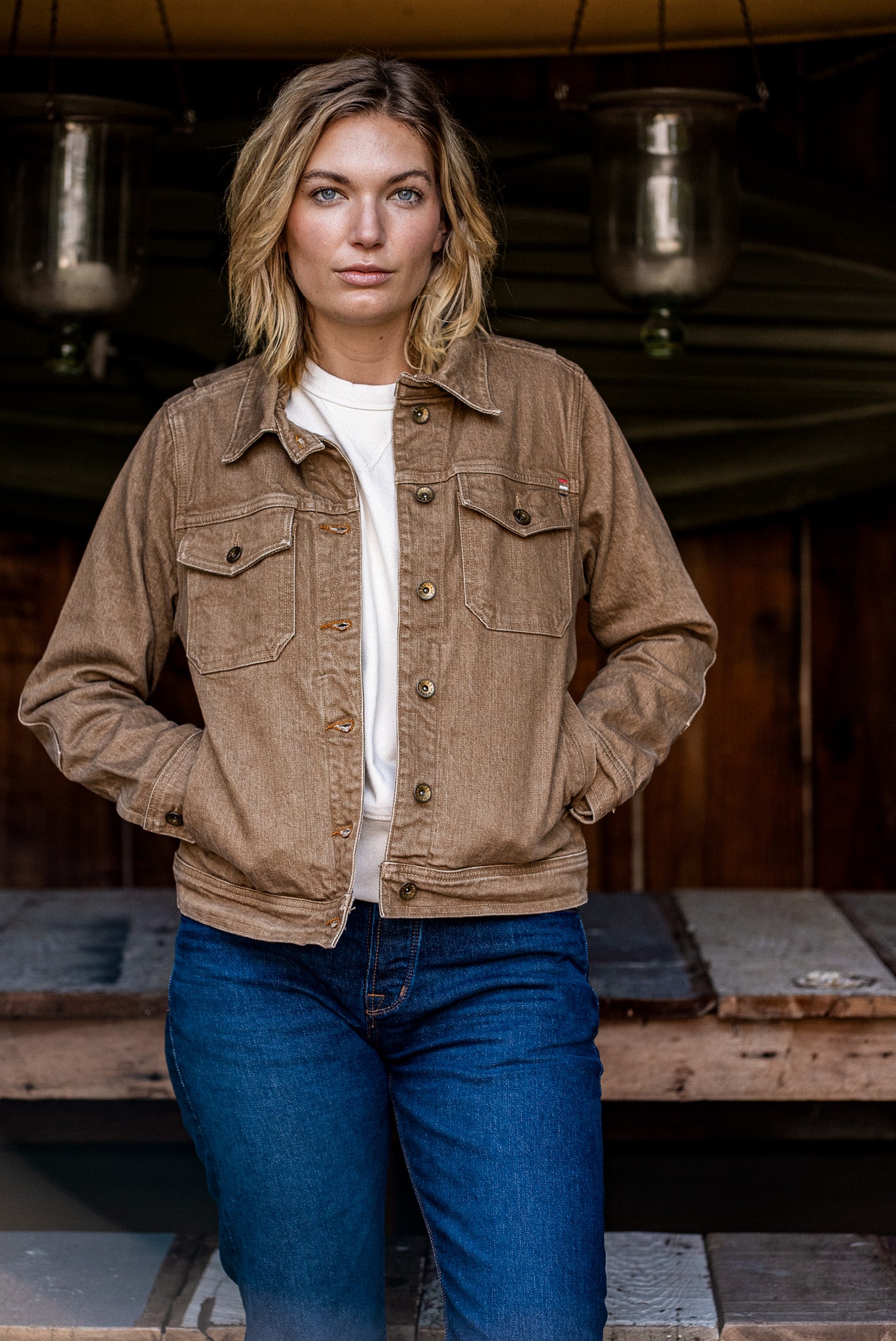 Model wearing the wheat-colored broken twill denim jacket over a white tee with blue jeans.