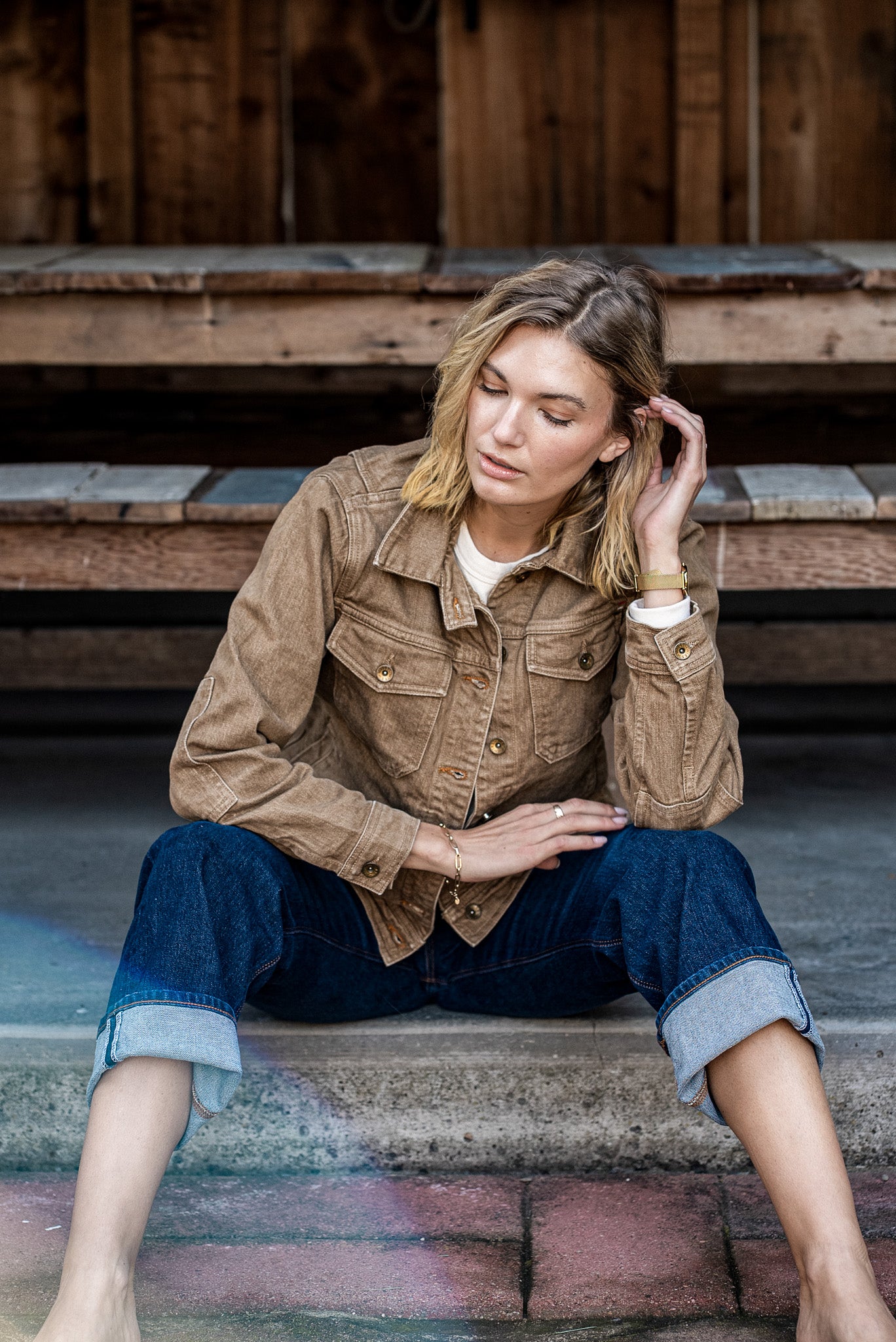 Wheat broken twill denim jacket worn with cuffed selvedge jeans on wooden steps.