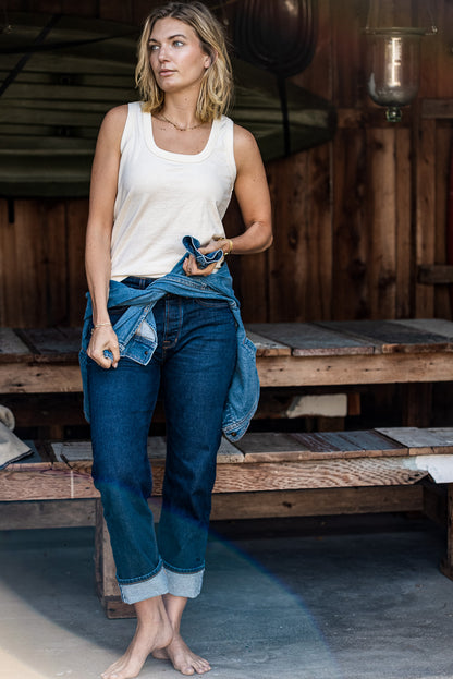Woman wearing the natural cotton Reyes tank with cuffed denim jeans and a denim shirt tied at the waist.
