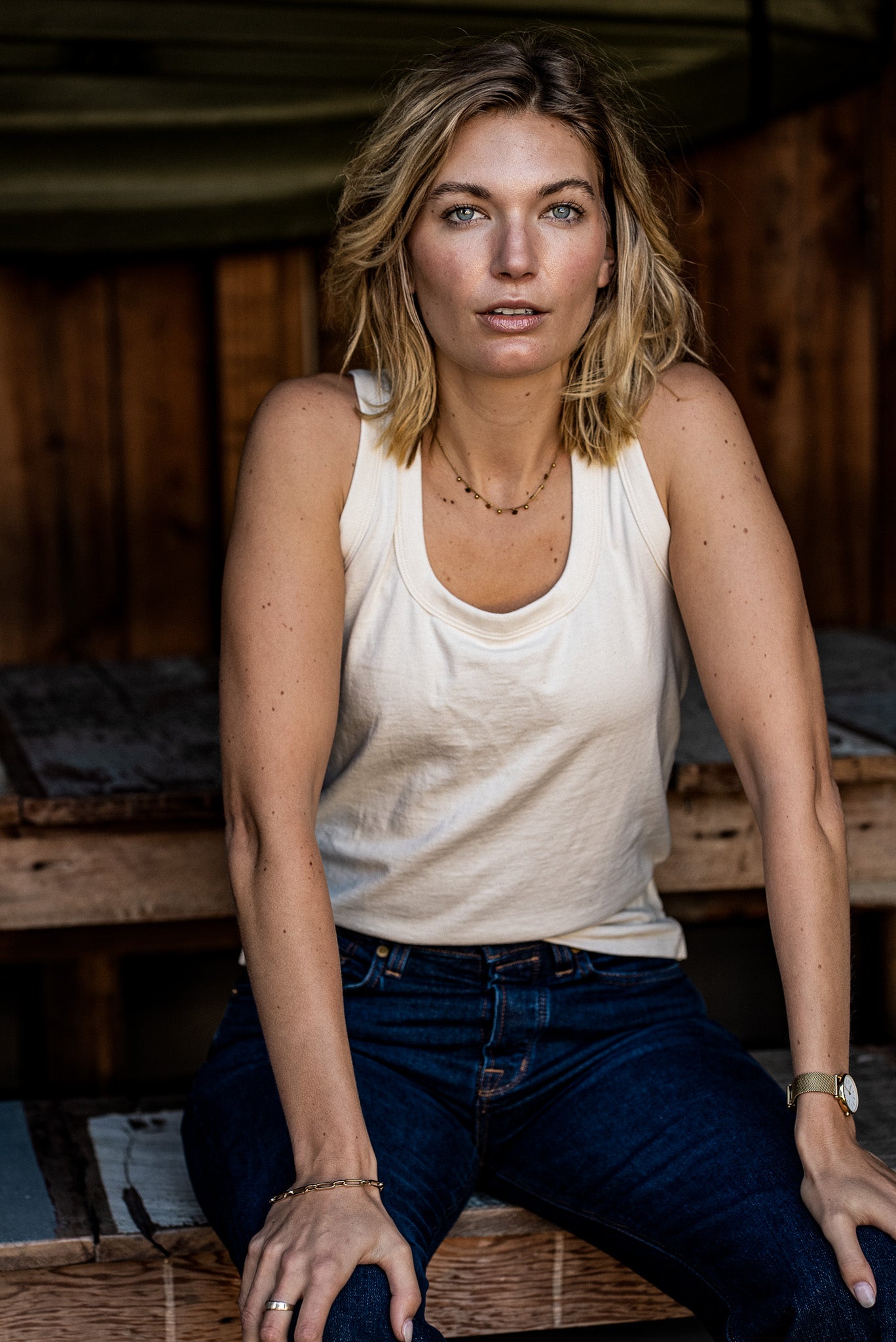 Model wearing the natural cotton Reyes tank with a scoop neck, paired with dark denim jeans.