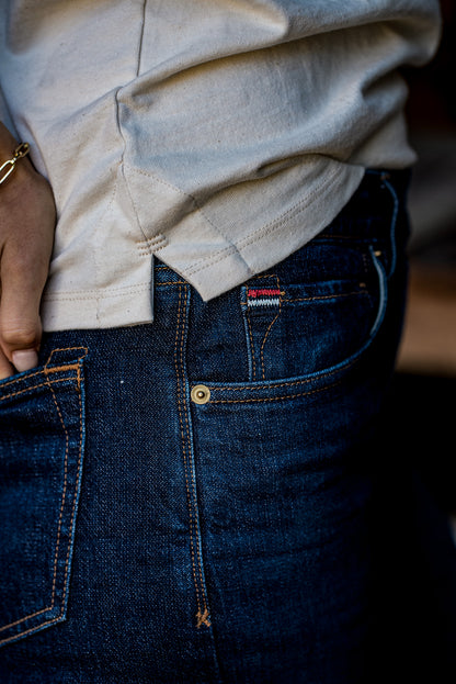 Close-up of the natural cotton Reyes tank hem tucked over dark selvedge denim jeans.