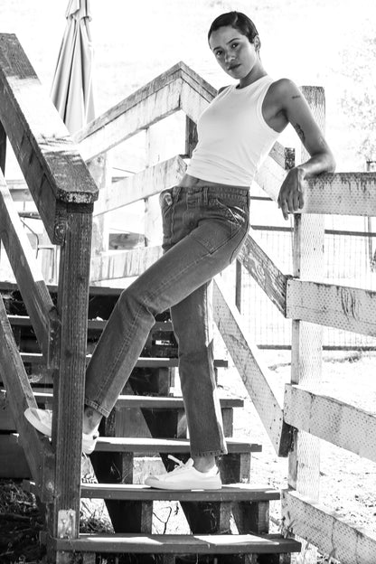 Women’s salt wash designer jeans styled with a white tank top and sneakers, featuring a high rise fit, straight leg silhouette, and structured seams for a classic, modern look