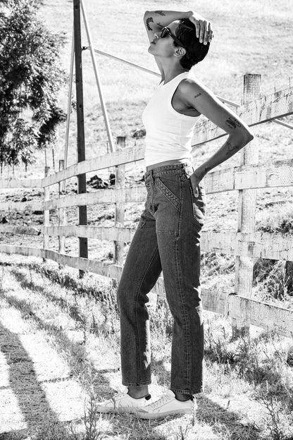 Women’s ocean wash designer denim jeans styled with a white tank top and sneakers, featuring a high rise fit, straight leg silhouette, and vintage-inspired stitching for a modern classic look