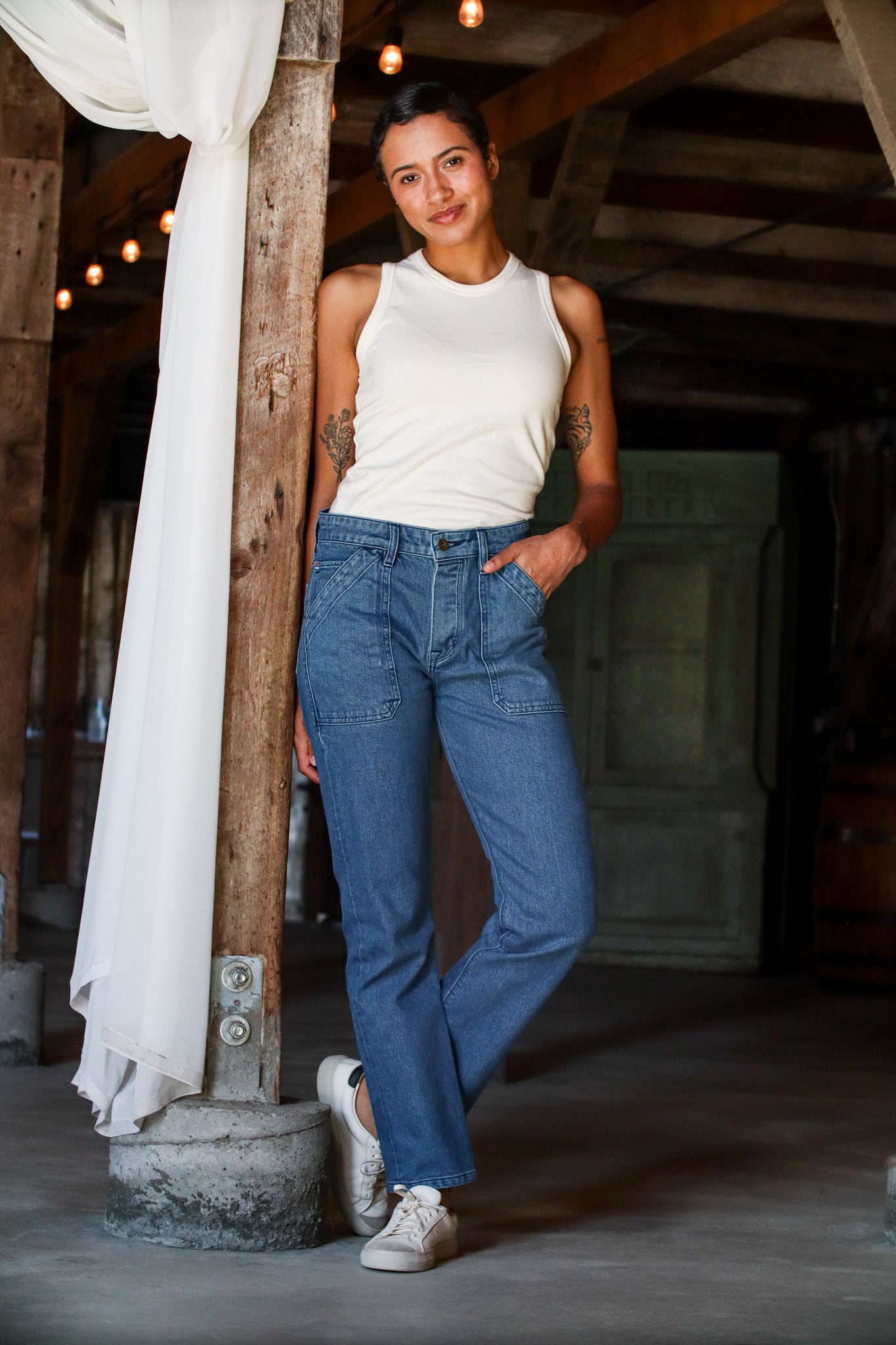 USA made salt wash jeans for women styled with a white tank top and sneakers, featuring a light blue wash, high rise fit, and utility pocket detailing for a clean, casual look