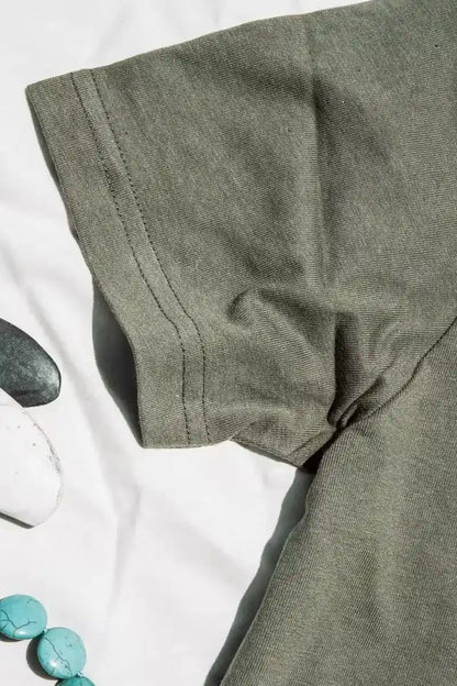 Close-up of olive heavyweight cotton tee sleeve showing double-stitched hem, styled with stones and turquoise beads.