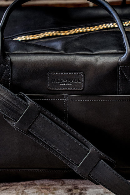 Black Horween leather weekender bag with brass zipper and embossed Made in USA stamp.