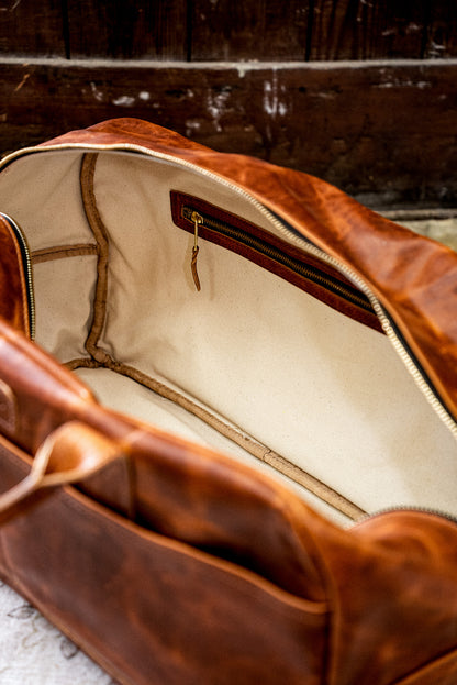 Interior of tan Horween leather weekender bag showing natural canvas lining and brass zip pocket.
