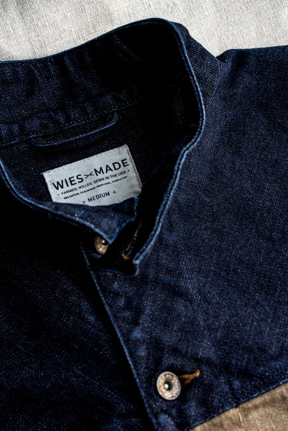 Close-up of indigo broken twill denim vest collar with WiesMade USA-made label and brass button.