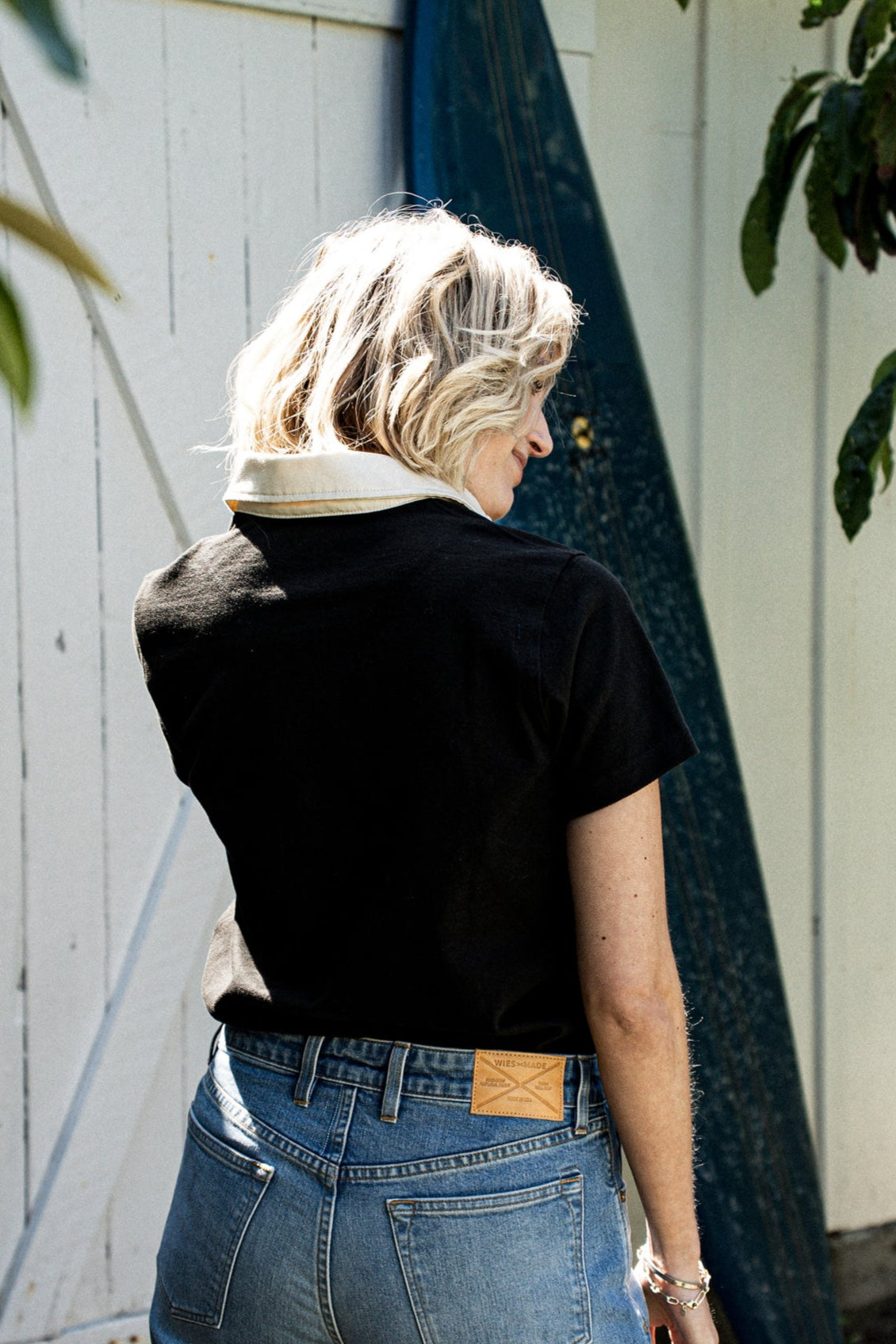 Back view of a black rugby jersey with cream collar, paired with WiesMade denim jeans outdoors.