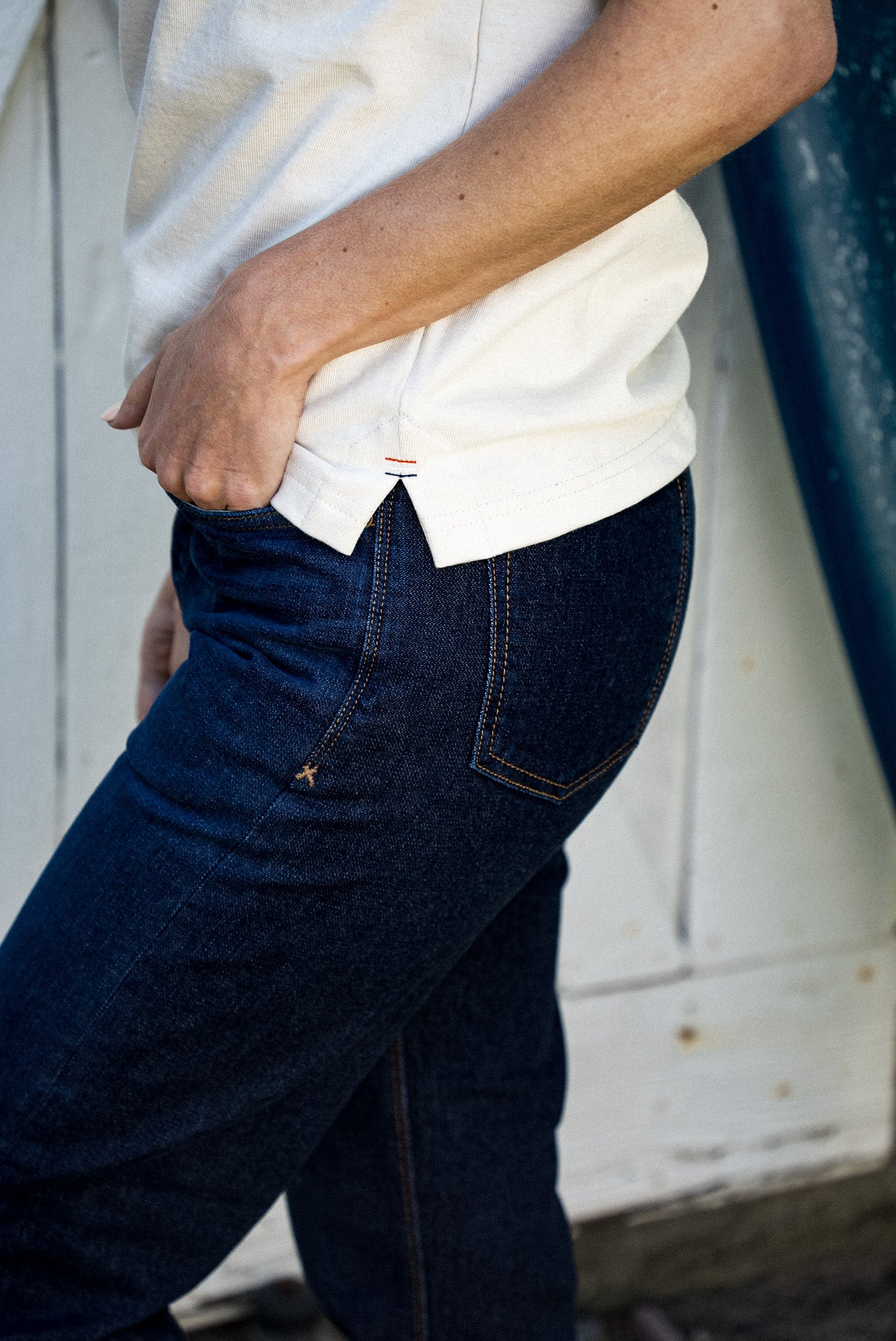 Side view of natural cotton rugby jersey hem detail paired with dark raw denim jeans.